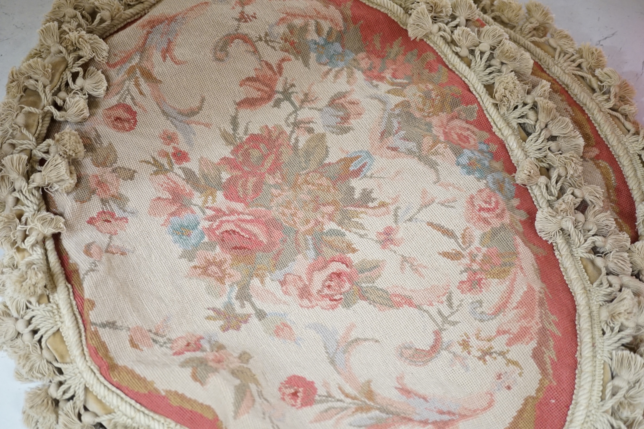 Four 20th century oval floral needleworked cushion covers with tasselled edging, 57cm wide